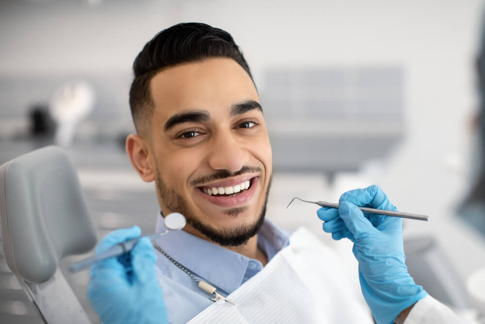 Smiling patient in dental chair with dental tools, highlighting cosmetic dentistry services at Broadway Dentistry.