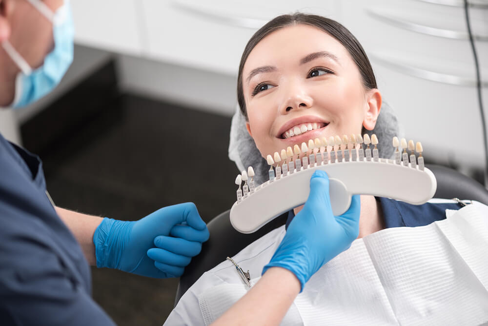 Patient smiling while comparing tooth shade options with a dental professional during a cosmetic dentistry consultation at Broadway Dentistry.